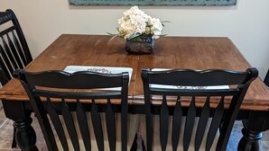 A dining table with a floral centerpiece, surrounded by four black chairs with woven seats.