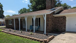 A two-story house with a covered porch, brick exterior, and a garage.