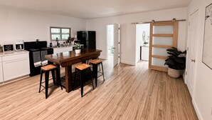 Una cocina moderna con una isla central, taburetes de madera y un refrigerador negro.