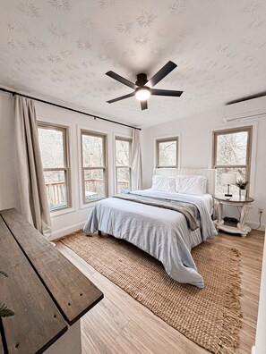 A bedroom with a bed, a ceiling fan, a window, a bedside table, and a wooden bench. - The River Side Lodge- With private boat dock on the KY river! (Harrodsburg)