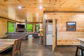 A wooden cabin interior with a dining area, living room, and kitchen.