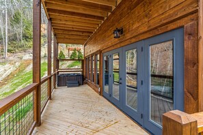 Une terrasse en bois avec une rambarde, de grandes fenêtres et une vue sur le paysage environnant.