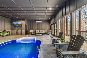 Relax by the pool with a clear view of the surrounding landscape, featuring comfortable seating and a TV.