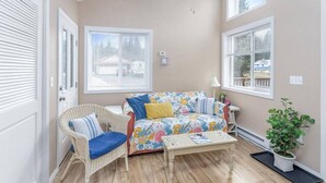 Un salon chaleureux avec un canapé à motifs floraux, un fauteuil en osier et une petite table basse.