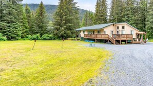 Un chalet doté d’une terrasse, de meubles de jardin et offrant une vue sur la forêt.