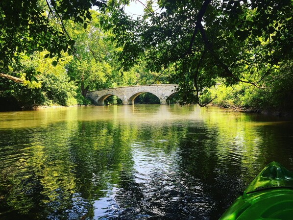Un puente de piedra sobre un río tranquilo, rodeado de abundante vegetación.