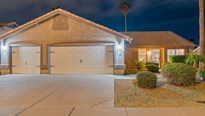 A two-story house with a garage, a well-lit entrance, and a landscaped front yard.