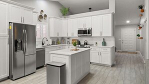 A modern kitchen with white cabinetry, stainless steel appliances, and a central island.
