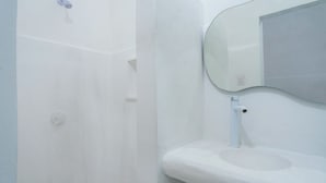Un baño con lavabo blanco, espejo y ducha.
