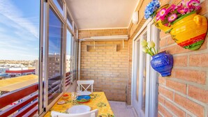 A balcony with a table set for two, a white chair, and a vase with flowers. - Nice apartment in Torrevieja with WiFi (Torrevieja)
