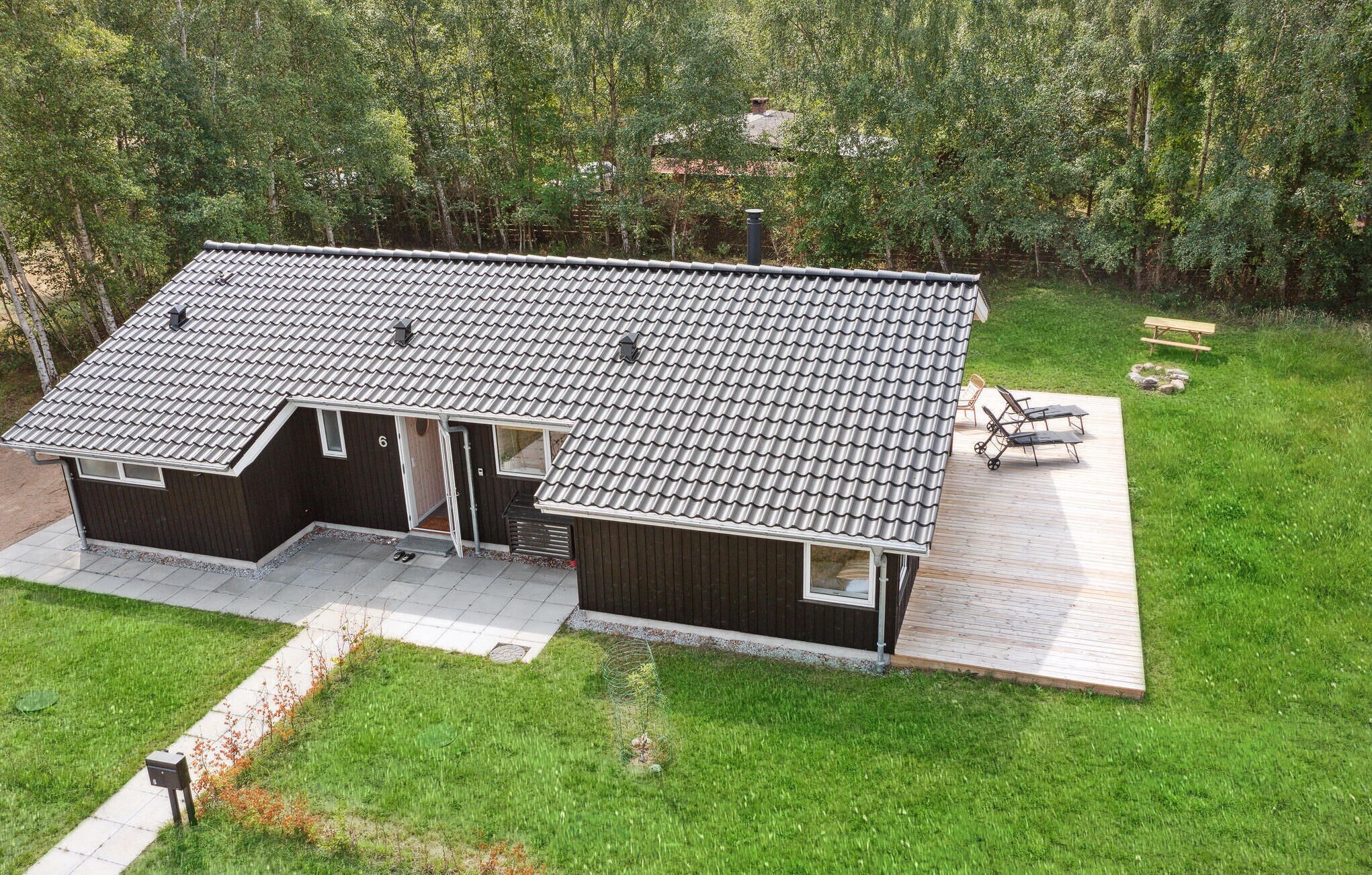 Een modern huis met een pannendak, een houten terras en een kleine zithoek buiten.