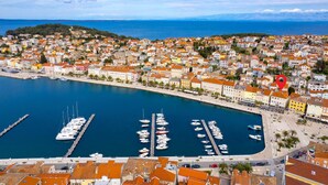 Une ville côtière dotée d’un port de plaisance rempli de bateaux, entourée de bâtiments aux couleurs vives et offrant une vue dégagée sur la mer.