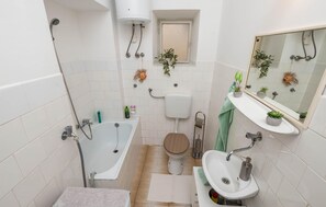 Une petite salle de bain comprenant une baignoire, des toilettes et un lavabo.
