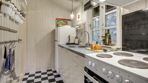 Una cocina con piso a cuadros, estufa, pileta y varios utensilios.