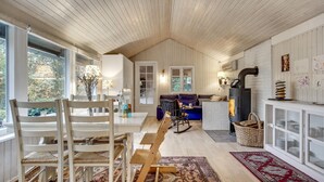 Un interior acogedor de cabaña con comedor, sofá, chimenea y zona de cocina.