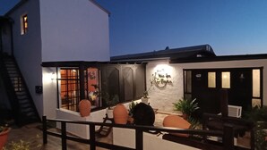 Un edificio moderno con fachada blanca, una escalera de madera y un balcón con macetas.