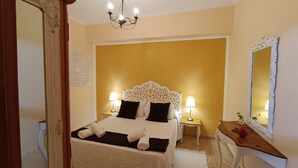 Una habitación de hotel con cama, dos lámparas de noche, un espejo y un candelabro.