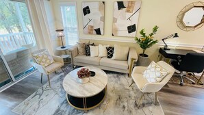 A modern living room with a sofa, two armchairs, a coffee table, and abstract wall art. - Fairways gorgeous 2bdr condo (Myrtle Beach)