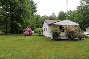 A small, single-story house with a porch, surrounded by a grassy yard and trees. - Pymatuning Lake Walking distance to Espyville Marina! (Pymatuning Central)