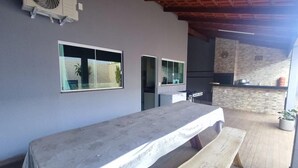 Une longue table recouverte d’une nappe, un ventilateur et un mur de pierre en arrière-plan.