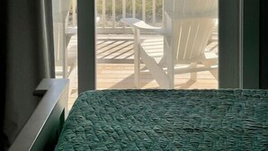 Une chambre avec un lit, une vue sur la plage et une chaise blanche sur le balcon.