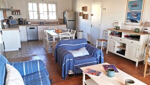 A cozy living room with a sofa and a coffee table, a dining area with a table and chairs, and a kitchen with a refrigerator and a microwave. - Le Clos de la Guittière - 6 people (Talmont-Saint-Hilaire)