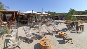 An outdoor seating area with sun loungers and tables, surrounded by umbrellas and wooden structures. - Le Clos de la Guittière - 6 people (Talmont-Saint-Hilaire)