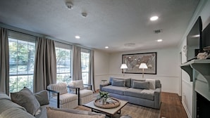 A modern living room with a grey sofa, striped armchairs, a coffee table with a decorative tray, and a fireplace. - Serene Home in Fondren Location Near Hospitals (Jackson)