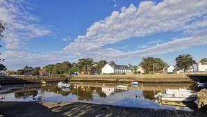 A riverside view with boats docked, a bridge, and buildings along the shore. - Carnac 3 Pièces Duplex, 4 Personnes 150m Plage (CARNAC)