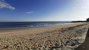 A sandy beach with footprints leading to the water, a clear sky, and a distant shoreline. - Carnac 3 Pièces Duplex, 4 Personnes 150m Plage (CARNAC)
