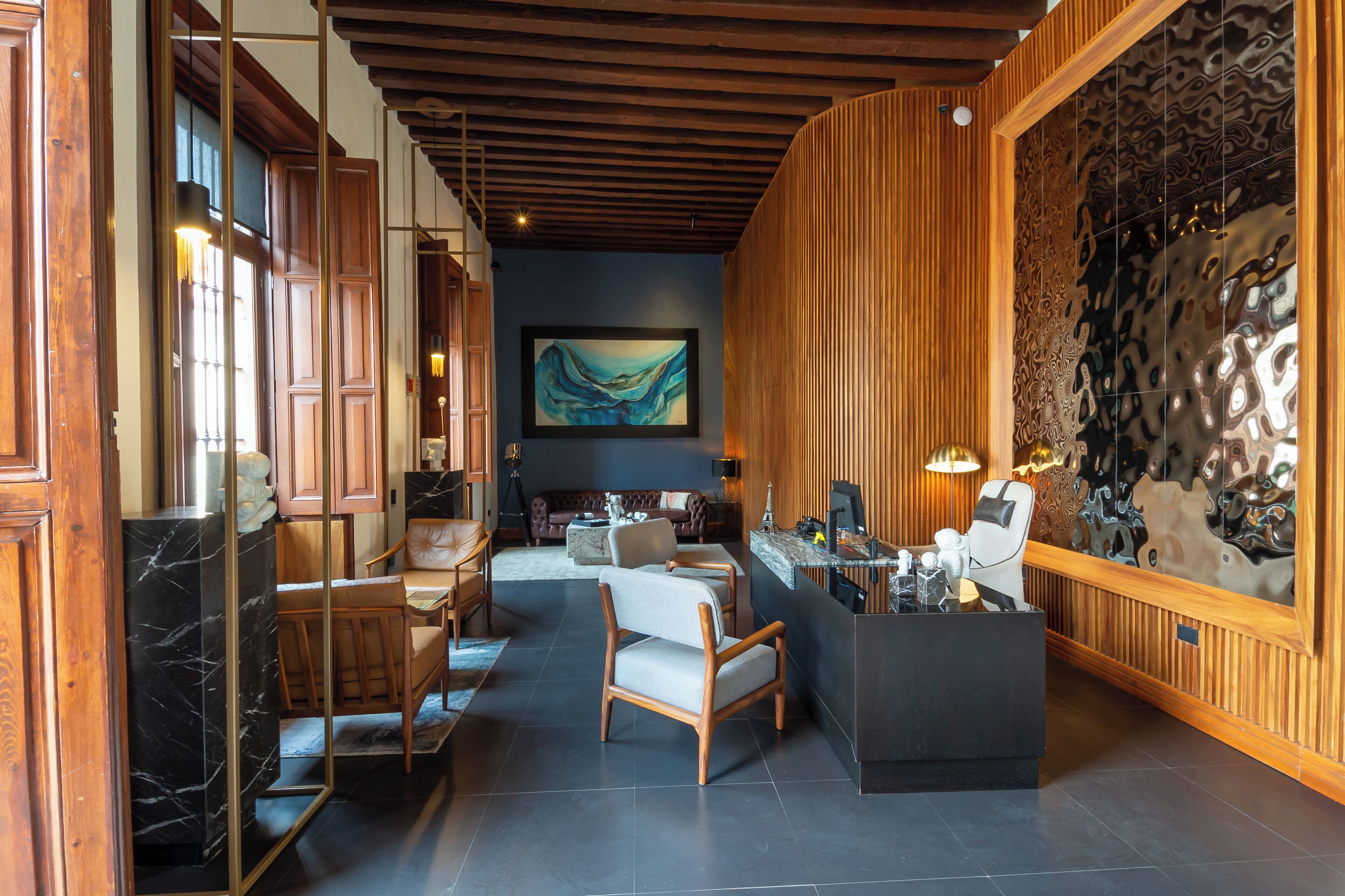 Un lobby moderno con paneles de madera, una recepción de mármol y un cuadro abstracto grande en la pared.