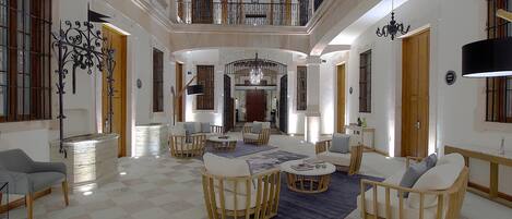 Un interior espacioso y elegantemente decorado, con un techo alto, una araña central y un balcón con vistas a la zona.