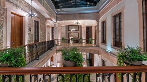 Ein geräumiger Innenraum mit einem zentralen Atrium, Steinwänden und zahlreichen Blumentöpfen.