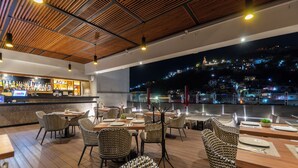 Ein Restaurant mit Holzboden, Korbstühlen und einer Bar.