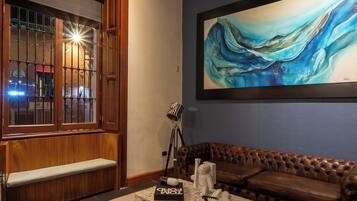 A cozy living room with a wooden bench, a marble coffee table, and a large abstract painting on the wall.
