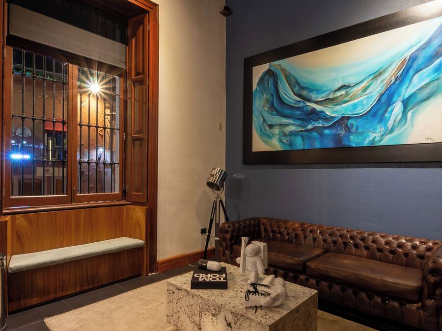 A cozy living room with a wooden bench, a marble coffee table, and a large abstract painting on the wall.