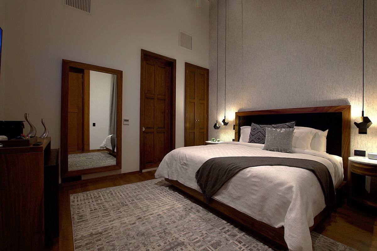 Ein Schlafzimmer mit einem großen Bett, einem Holzschrank und einem Spiegel.