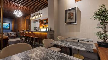 A modern restaurant with marble tables, wooden ceiling, and a bar area with stools.