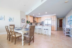 A spacious kitchen with modern appliances, a dining area with a white table and chairs, and artwork on the walls.