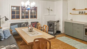 A cozy living room with a wooden dining table, chairs, a sofa, a fireplace, and a kitchen area with cabinets and a stove. - Awesome home in Fyresdal with kitchen (Fyresdal)