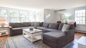 A modern living room with a sectional sofa, a coffee table, and a rug. - 100 Ft to Skaket Beach! (Orleans)