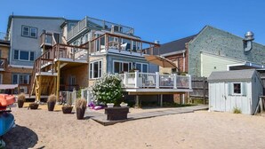 A multi-story residential building with a balcony, a small shed, and potted plants. - Renovated Oceanfront Penthouse! (Provincetown)
