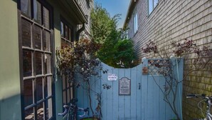 A narrow alleyway with a wooden fence, a bicycle, and a potted plant. - Renovated Oceanfront Penthouse! (Provincetown)