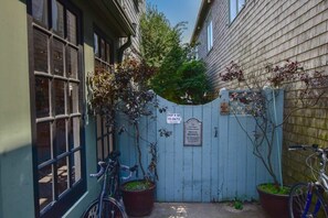 A narrow alleyway with a wooden fence, a bicycle, and a potted plant.