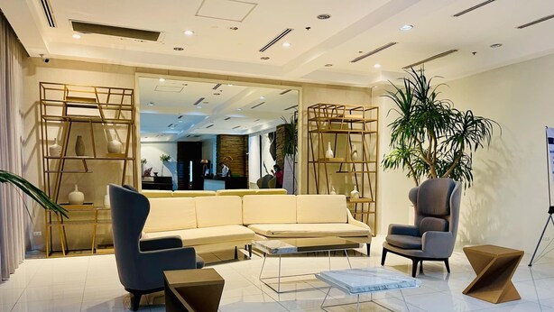 Un moderno vestíbulo de hotel con un sofá, sillones y una mesa de centro.