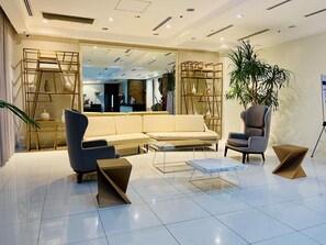 Un moderno vestíbulo de hotel con un sofá, sillones y una mesa de centro.