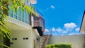 Un edificio moderno con fachada de vidrio, una escalera central y un césped bien cuidado.