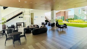 Un área de descanso al aire libre con disposición de asientos, una escalera y vista del exterior del edificio.