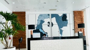 Un área de recepción moderna con un gran mapa mural, un mostrador de recepción y una planta en maceta.