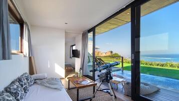 Una camera da letto con un'ampia finestra, un telescopio e vista sull'oceano.